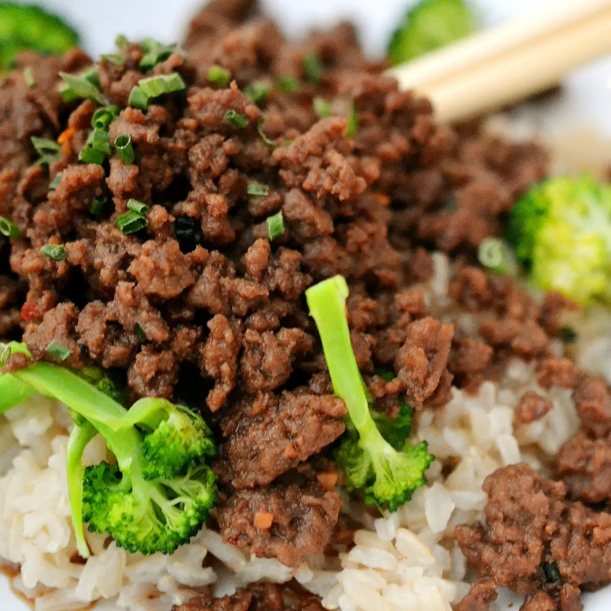 Cooked ground beef served over rice with broccoli and green onions