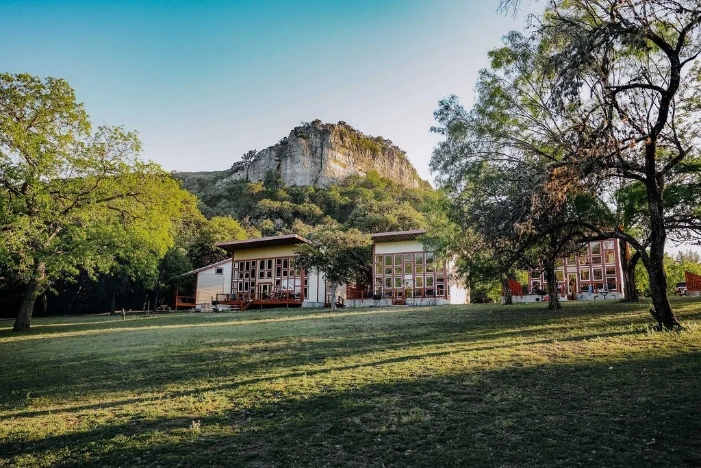 Cabins on a green lawn beneath the limestone bluff at 7 Bluff Cabins