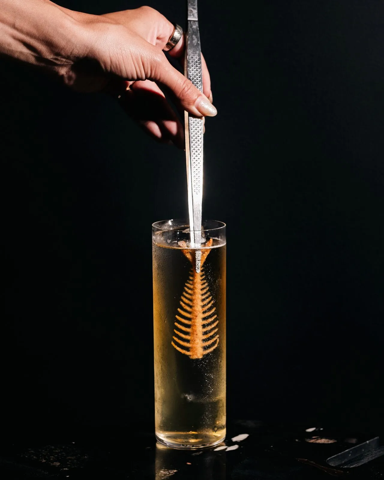 Papercut's tall Fisherman's Michelada with a fish-bone garnish against a black background