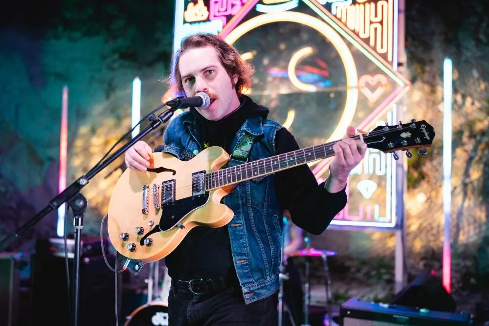 A guitarist performs in front of the neon stage at Cheer Up Charlies