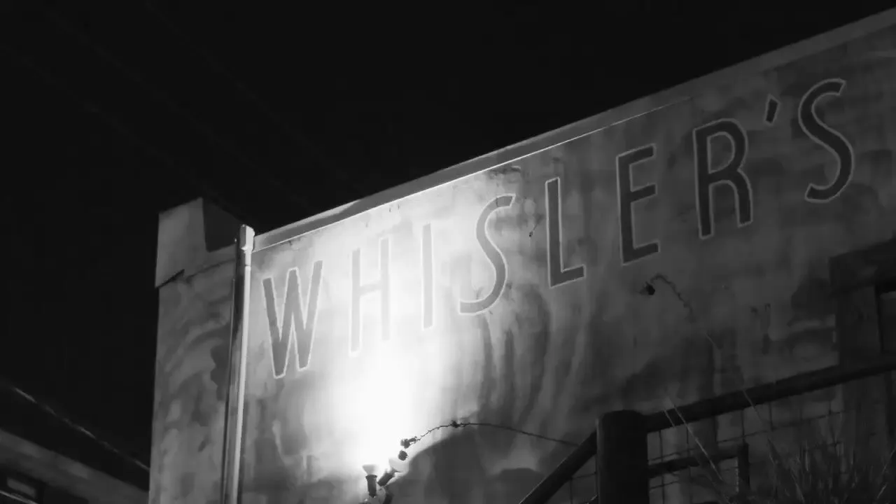 The Whisler's sign spans the bar's East Sixth Street facade at night