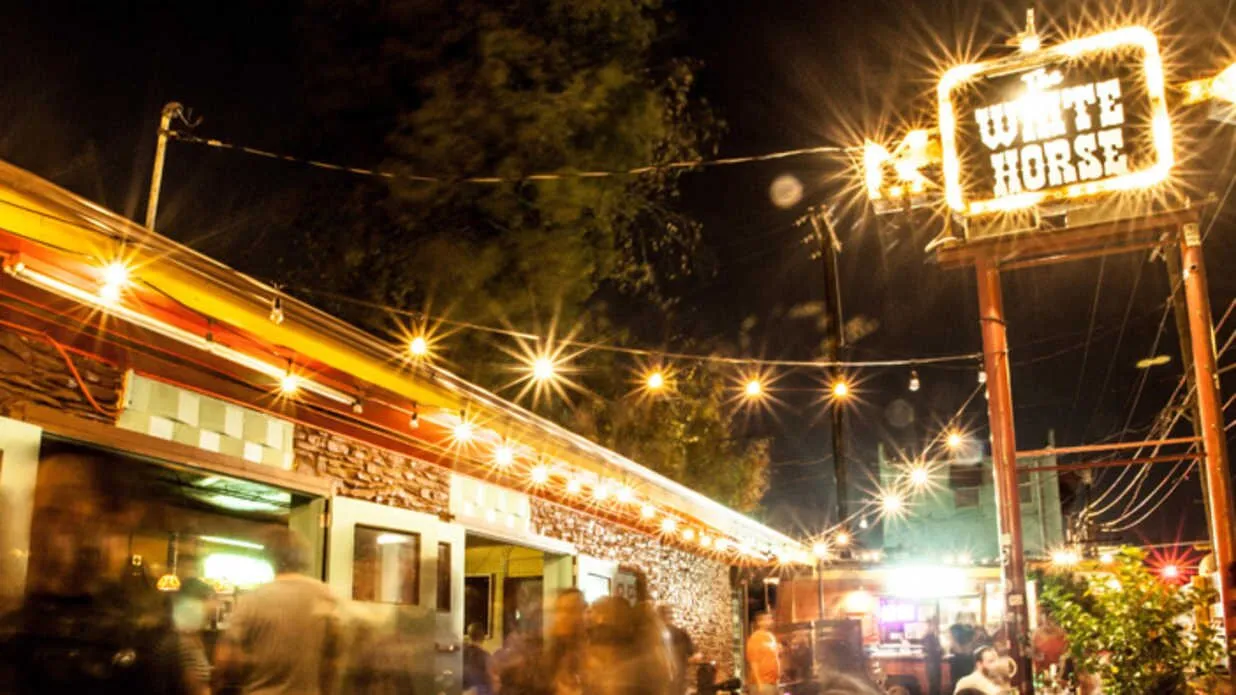 The White Horse marquee glows above its East Austin patio at night