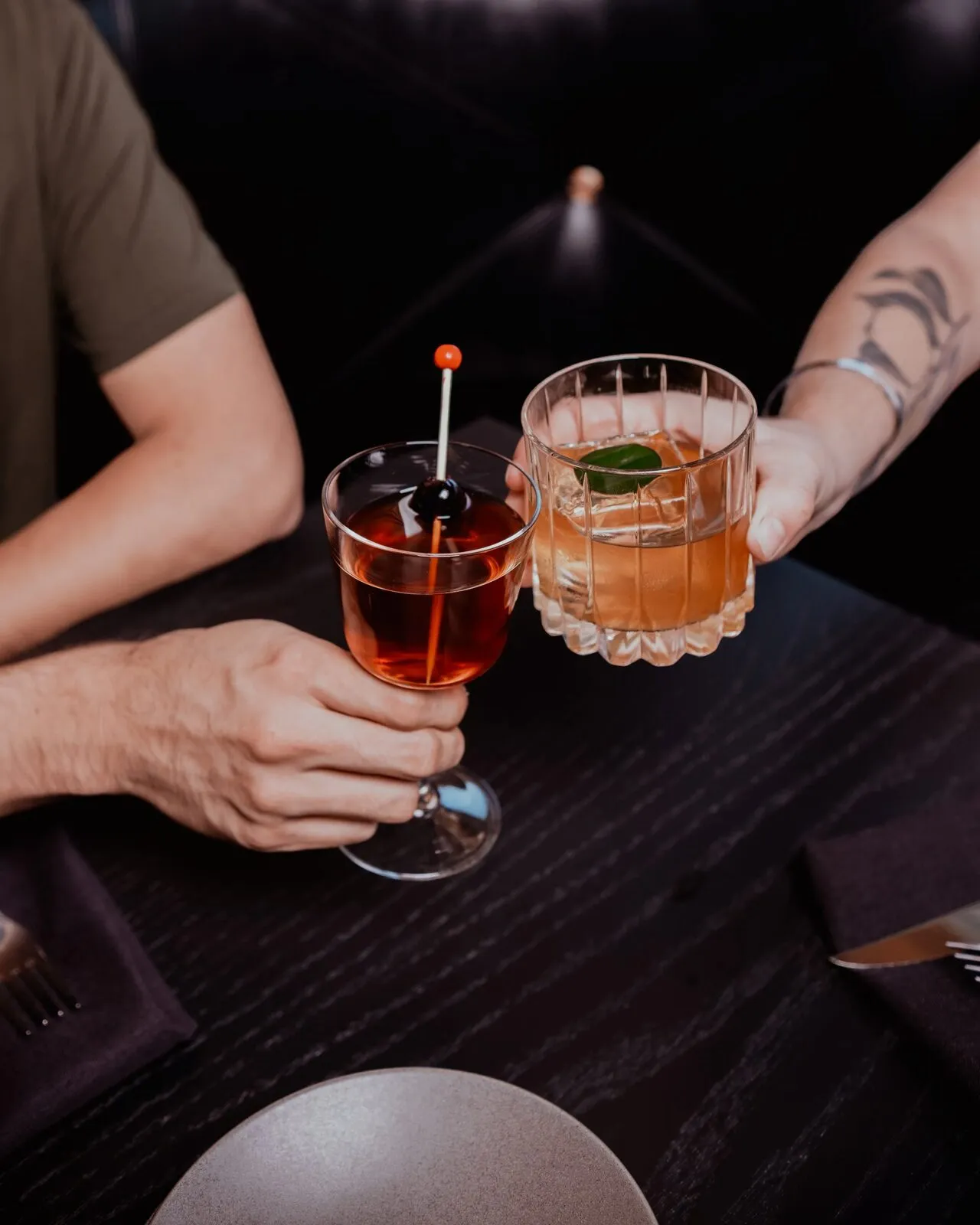 Two guests toast cocktails inside Drink.Well