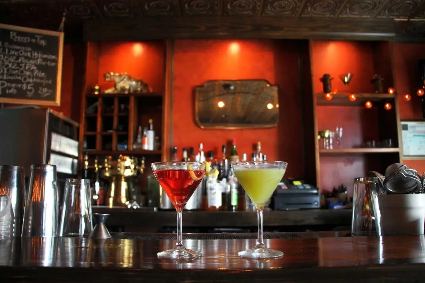 Two cocktails rest on the polished bar inside The Tigress Pub