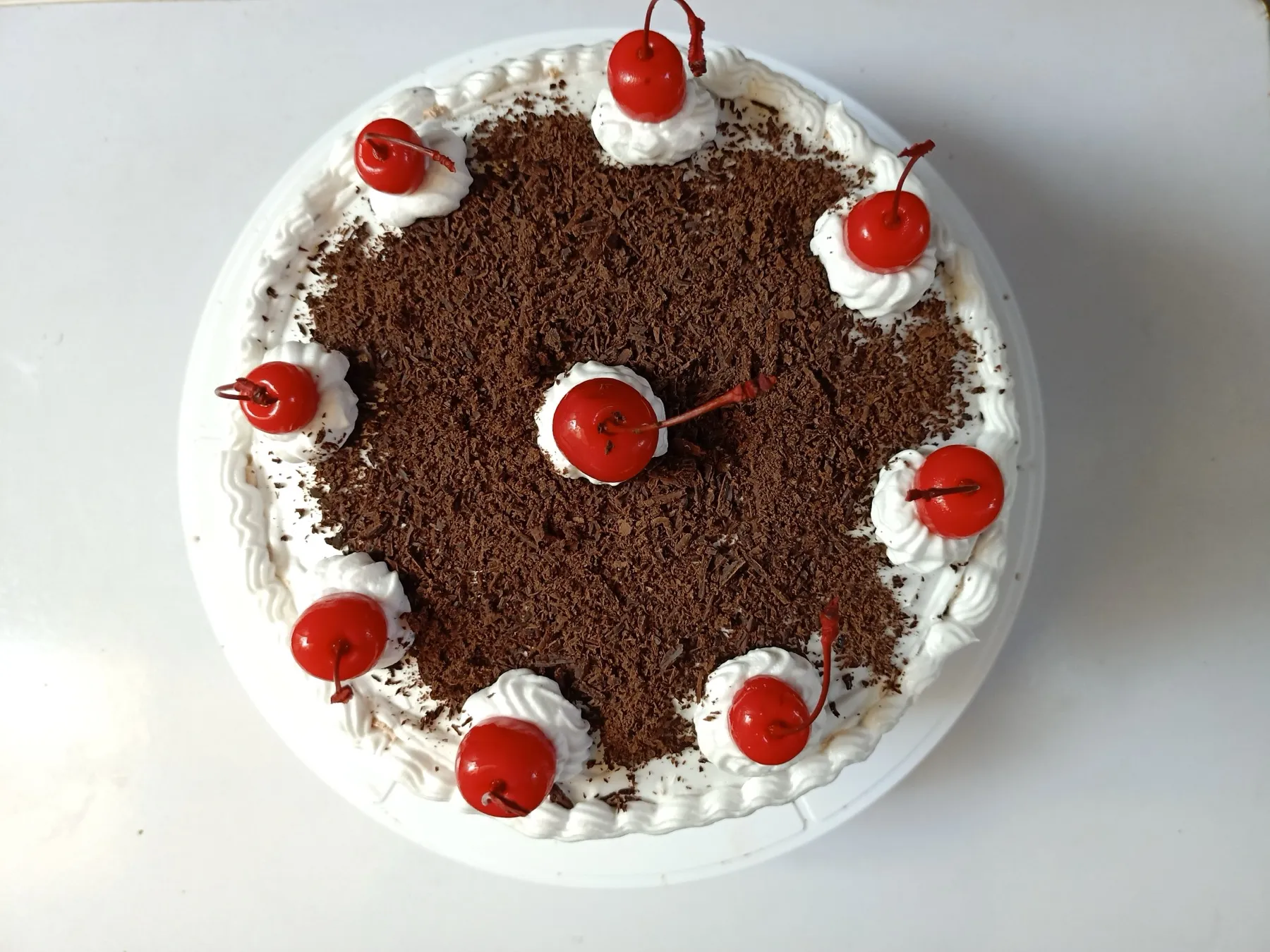A tall layered cake with cream and cherries