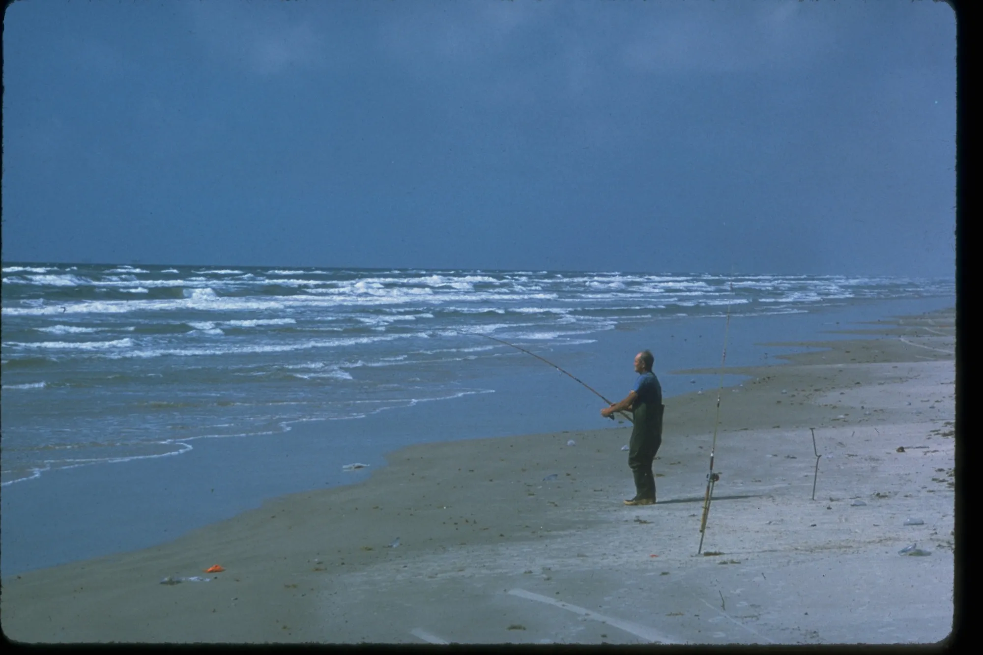 An angler standing in wet sand beside the surf at Padre Island National Seashore