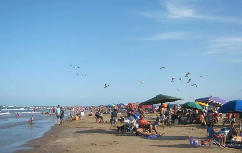 Families beneath colorful umbrellas along the Gulf beach at Isla Blanca Park