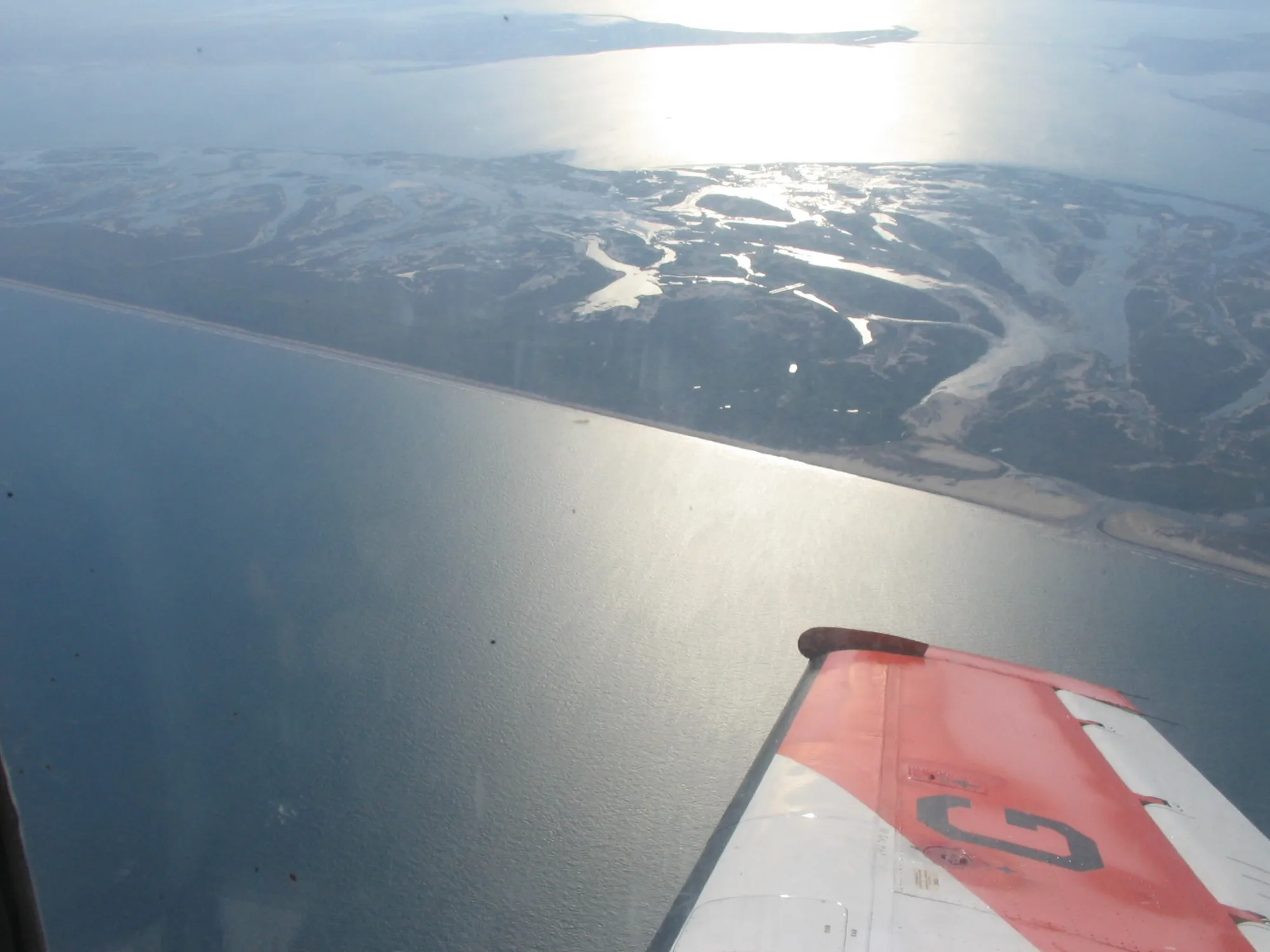 An aerial view over San Jose Island, with the wing of a small plane in the foreground