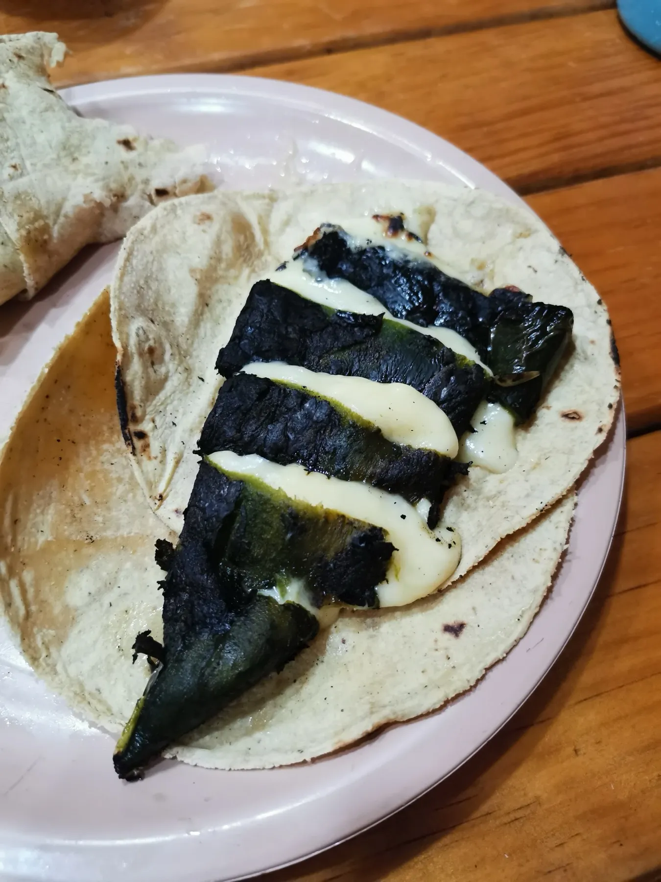 A folded corn tortilla taco filled with roasted chile poblano and melted cheese