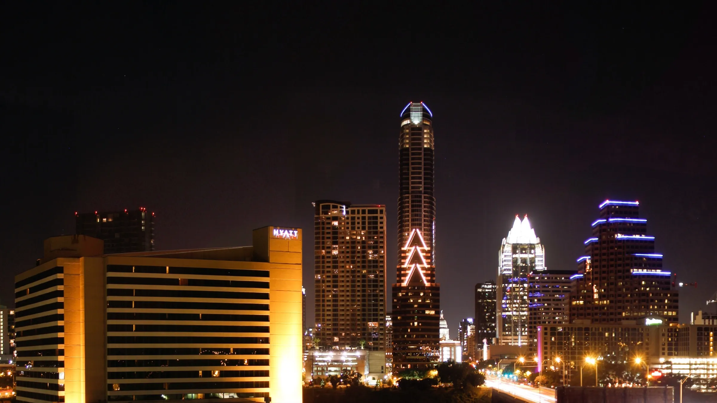 The downtown Austin skyline lit up at night, seen across Lady Bird Lake
