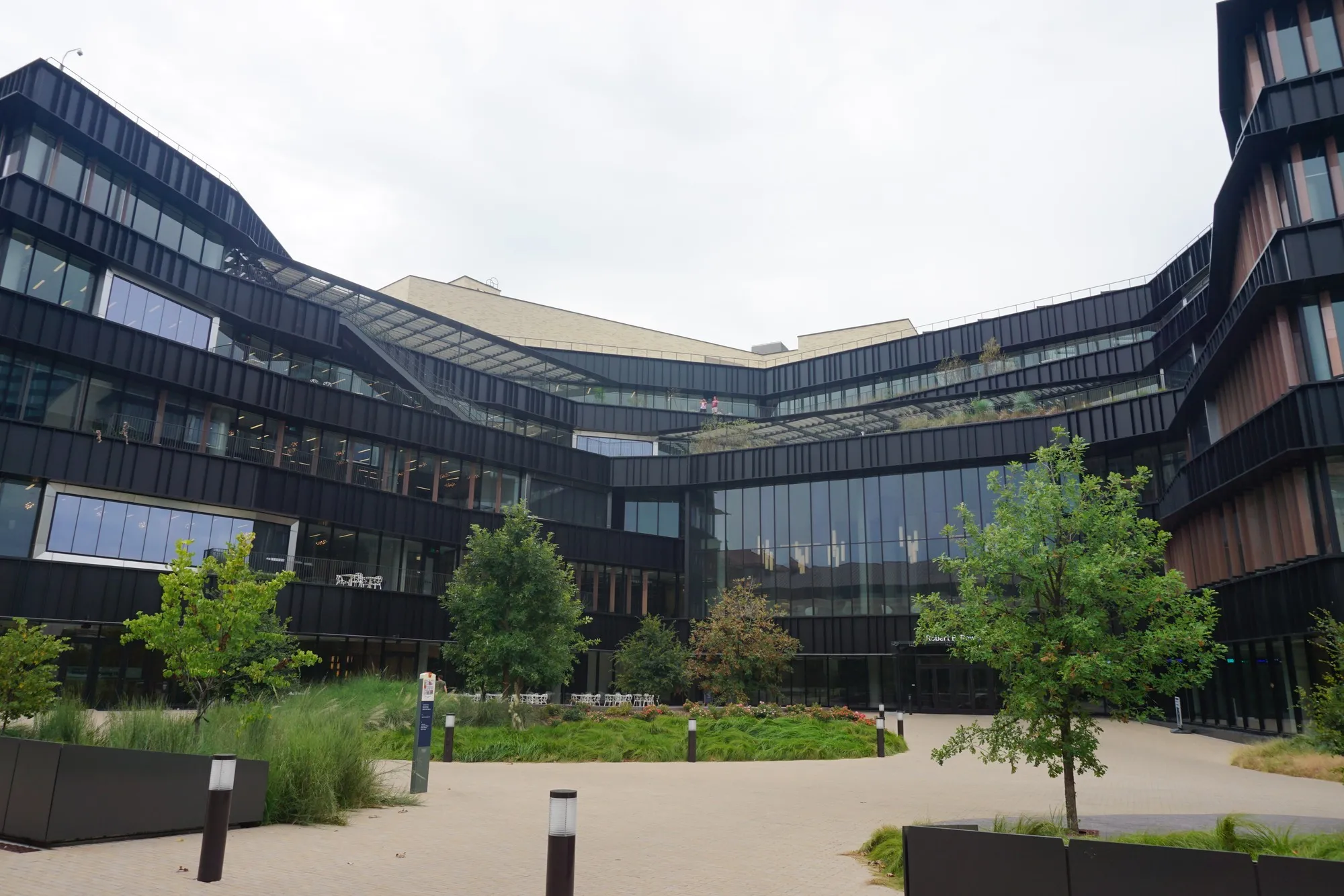 The landscaped courtyard and dark metal wings of Robert B. Rowling Hall at UT Austin