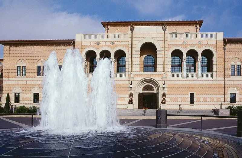 McNair Hall's brick-and-stone arched facade behind a fountain at Rice University