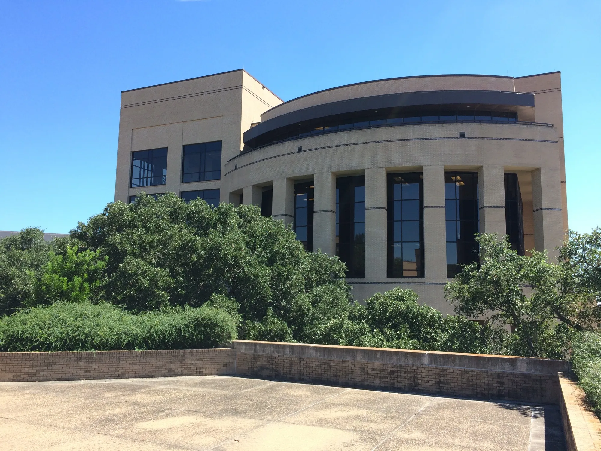 The curved tan-brick facade and tall windows of McCoy Hall at Texas State University