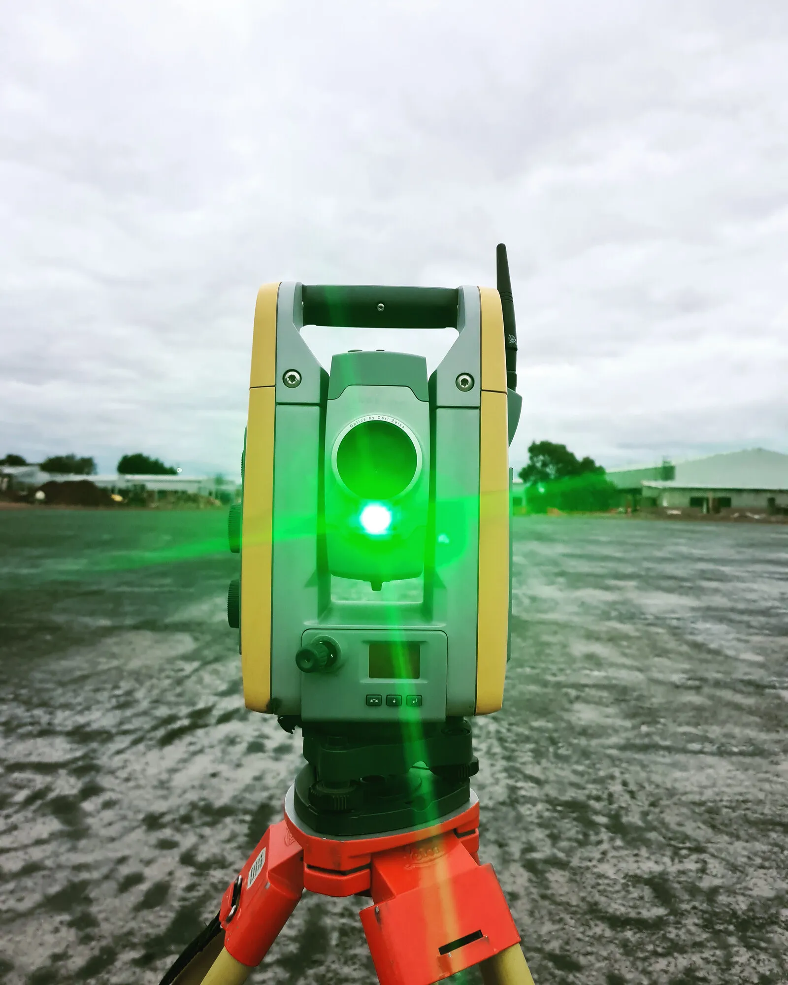 A robotic total station on a tripod at a cleared construction site