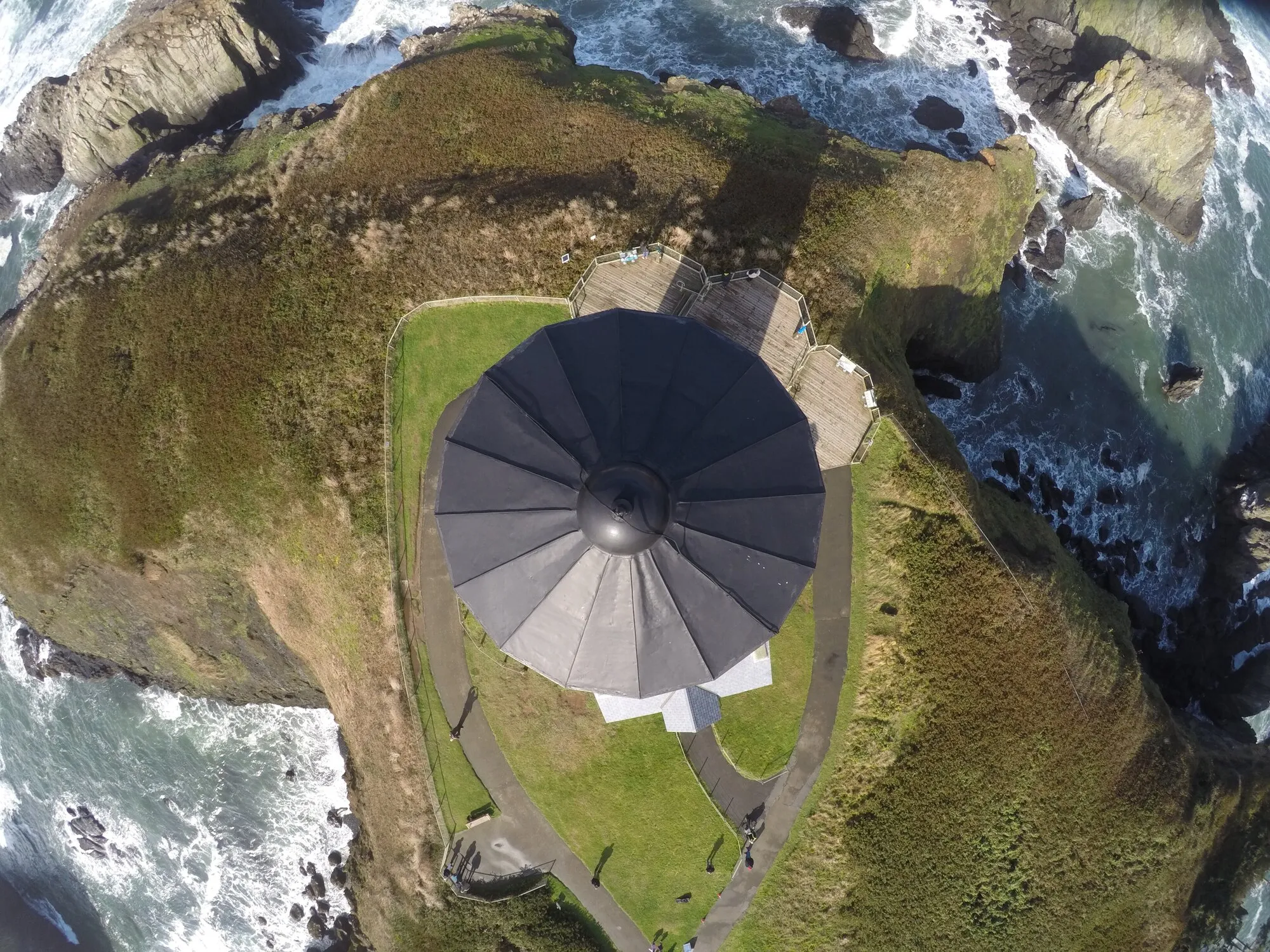 A drone hovering above the lantern roof of a coastal lighthouse during an inspection