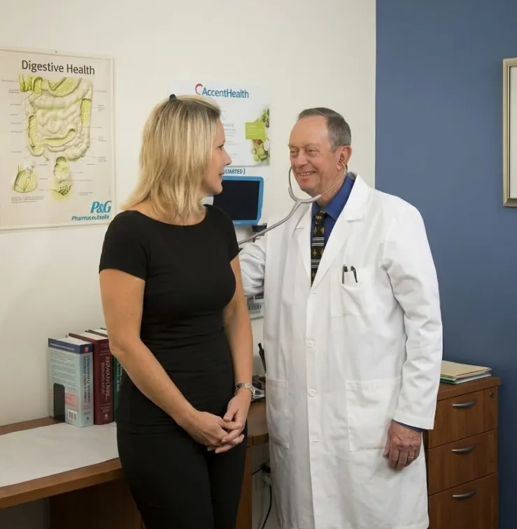 James Maher, MD, uses a stethoscope beside a woman in a medical office