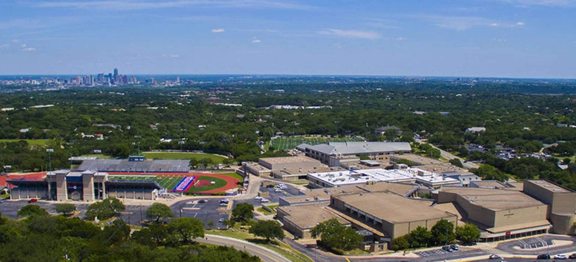 An aerial view of Westlake High School's campus and stadium with downtown Austin in the distance