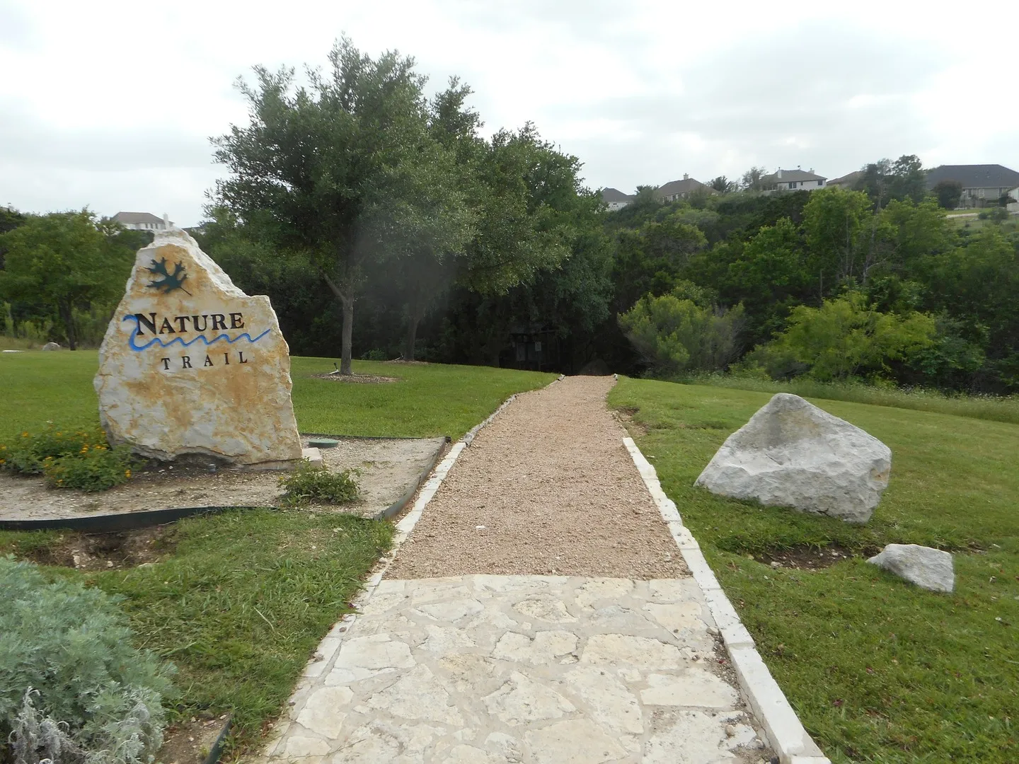 The stone Nature Trail entrance marker and a paved path in River Place