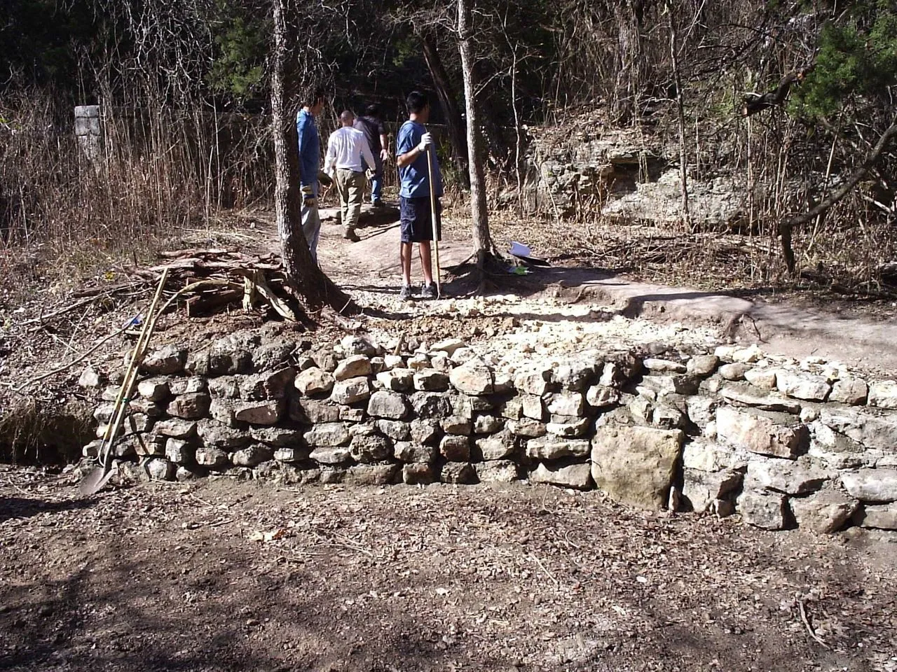 Hikers standing above a stone retaining wall at a Turkey Creek Trail crossing