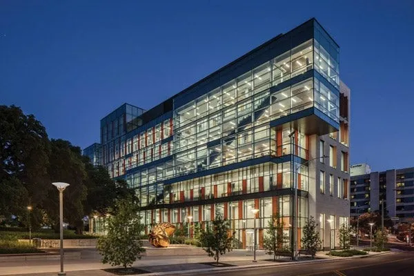 The glass-fronted Health Learning Building at Dell Medical School illuminated at dusk