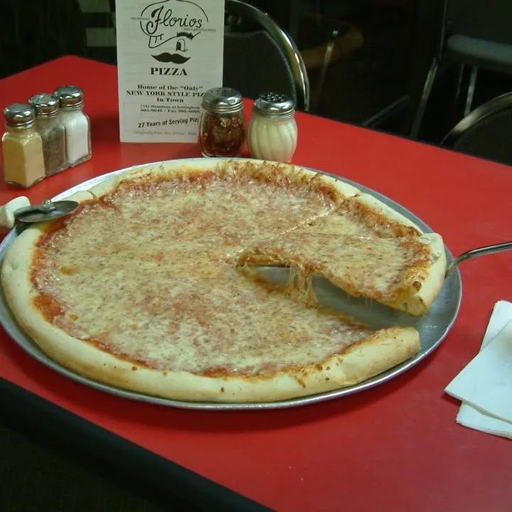 A Florio's cheese pizza with one slice removed, served on a metal tray over a red tablecloth
