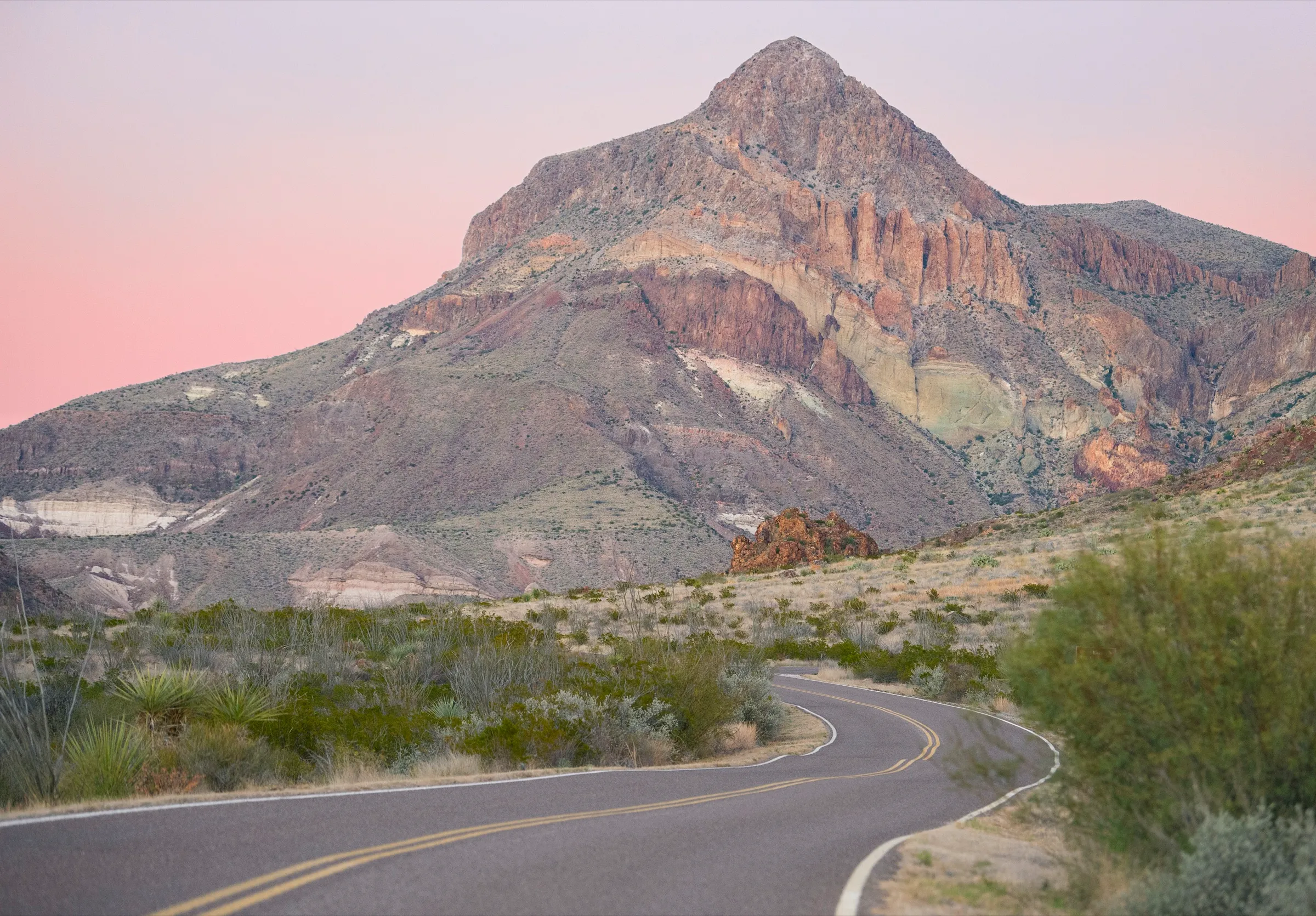 Desert peaks silhouetted against an orange sunset along the Ross Maxwell Scenic Drive in Big Bend National Park