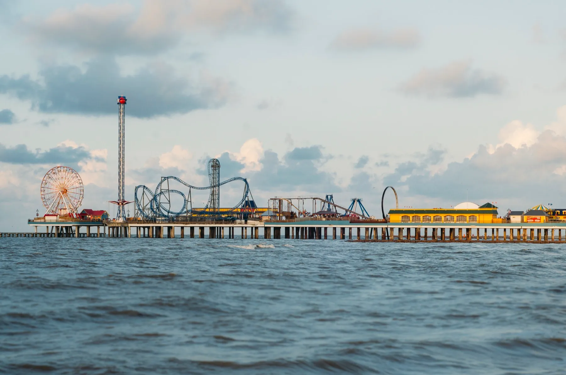 The rides and Ferris wheel of the Galveston Island Historic Pleasure Pier over the Gulf