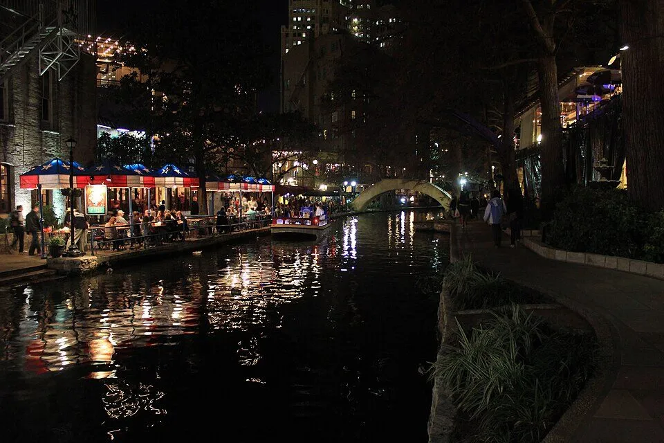 Restaurants and stone bridges lit along the San Antonio River Walk at night
