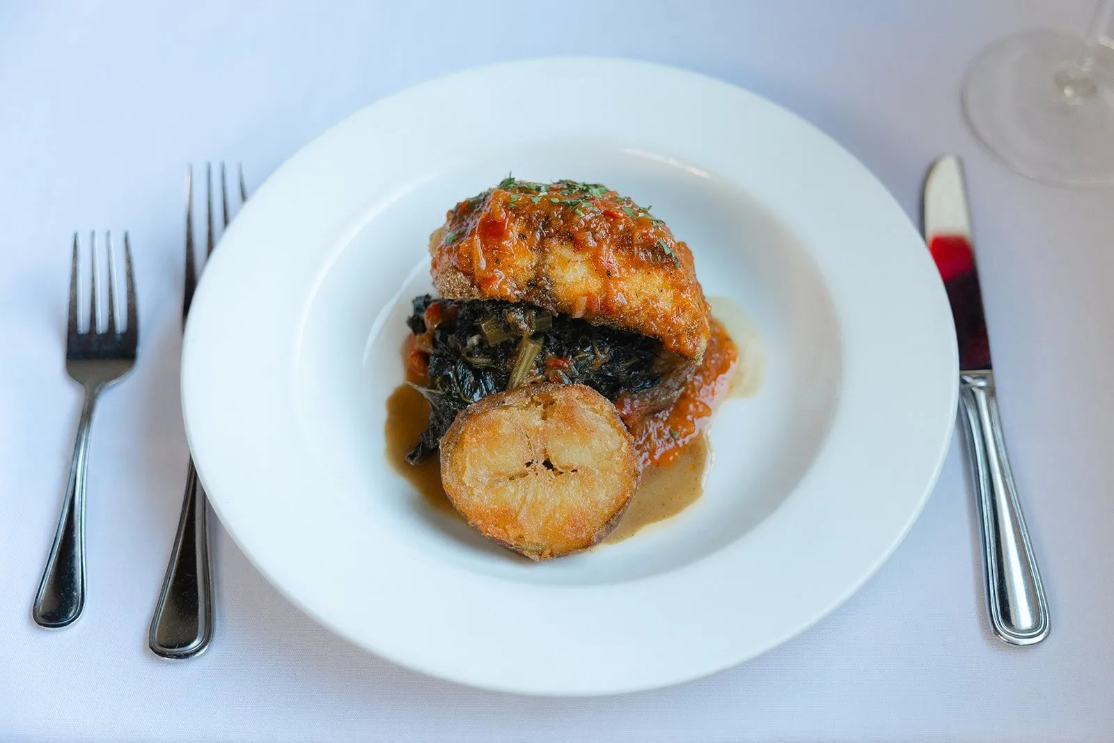 A seared scallop and fish fillet plated over vegetables at Ellerbe Fine Foods