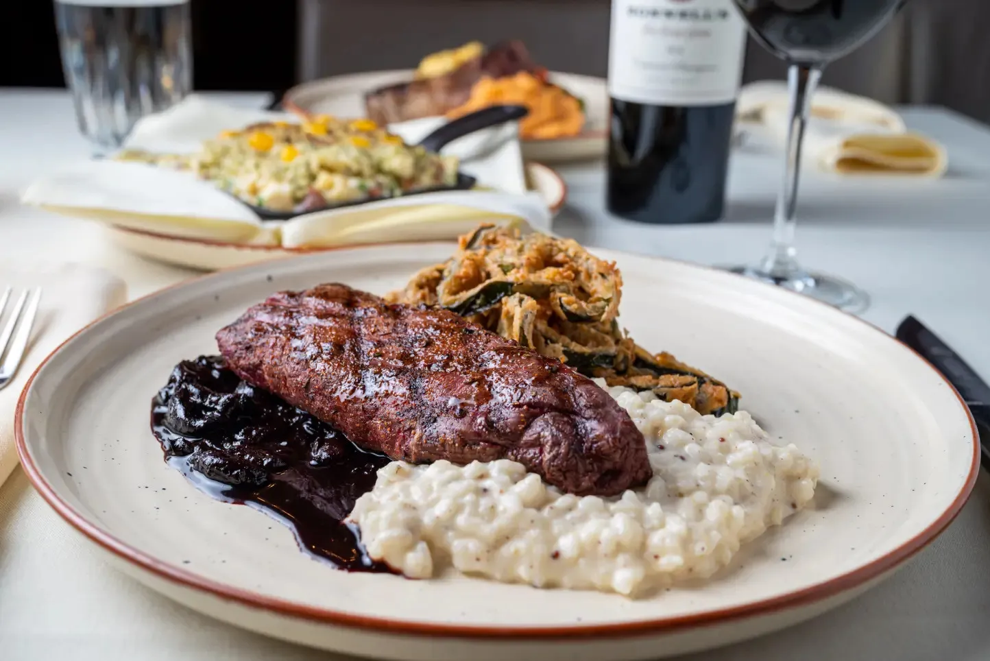 Bonnell's elk tenderloin plated with risotto, vegetables, and a dark fruit sauce