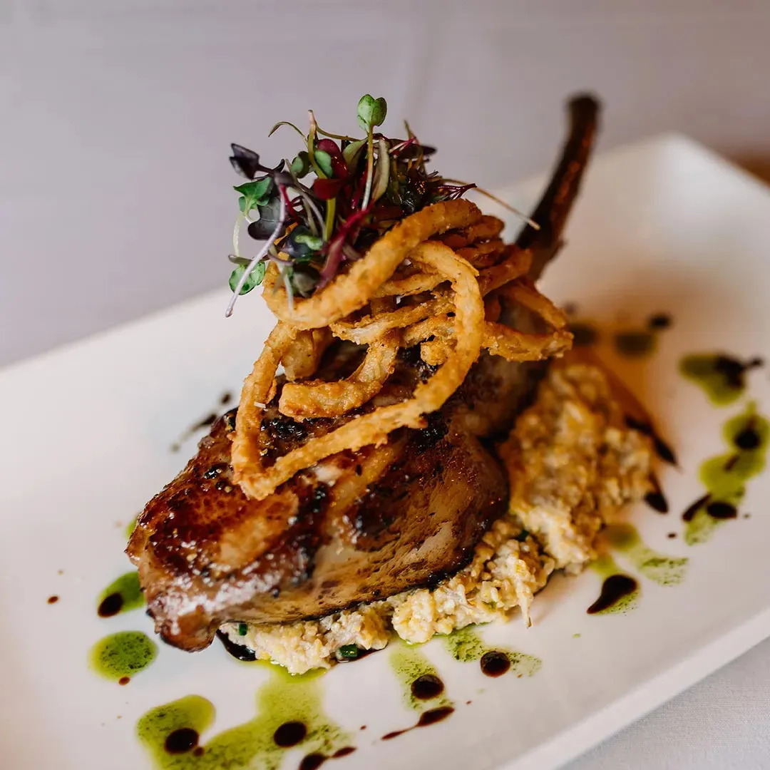 A grilled chop topped with crisp onion strings at Lonesome Dove Western Bistro
