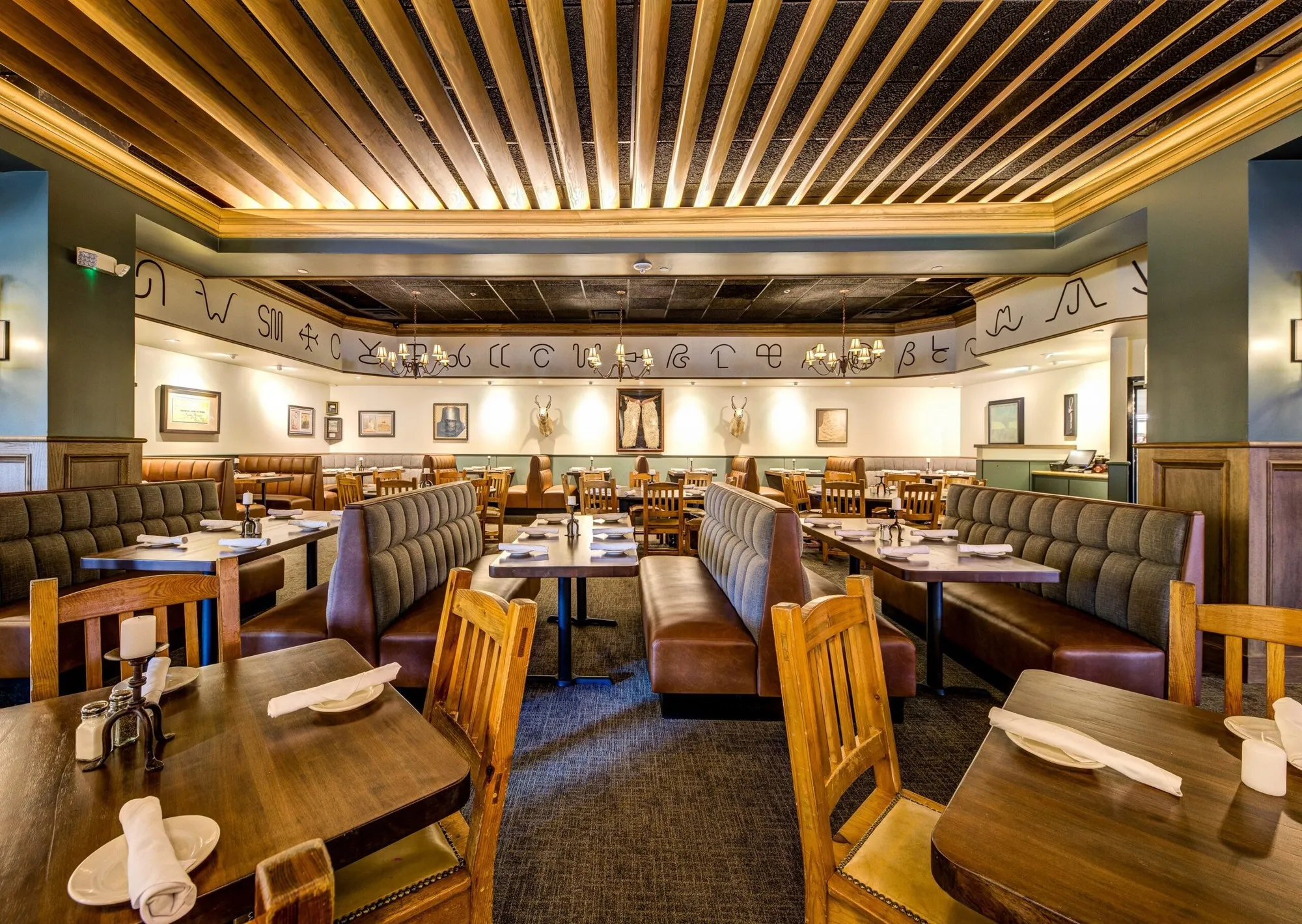Wood booths and set tables beneath a slatted ceiling in Reata's current Fort Worth dining room