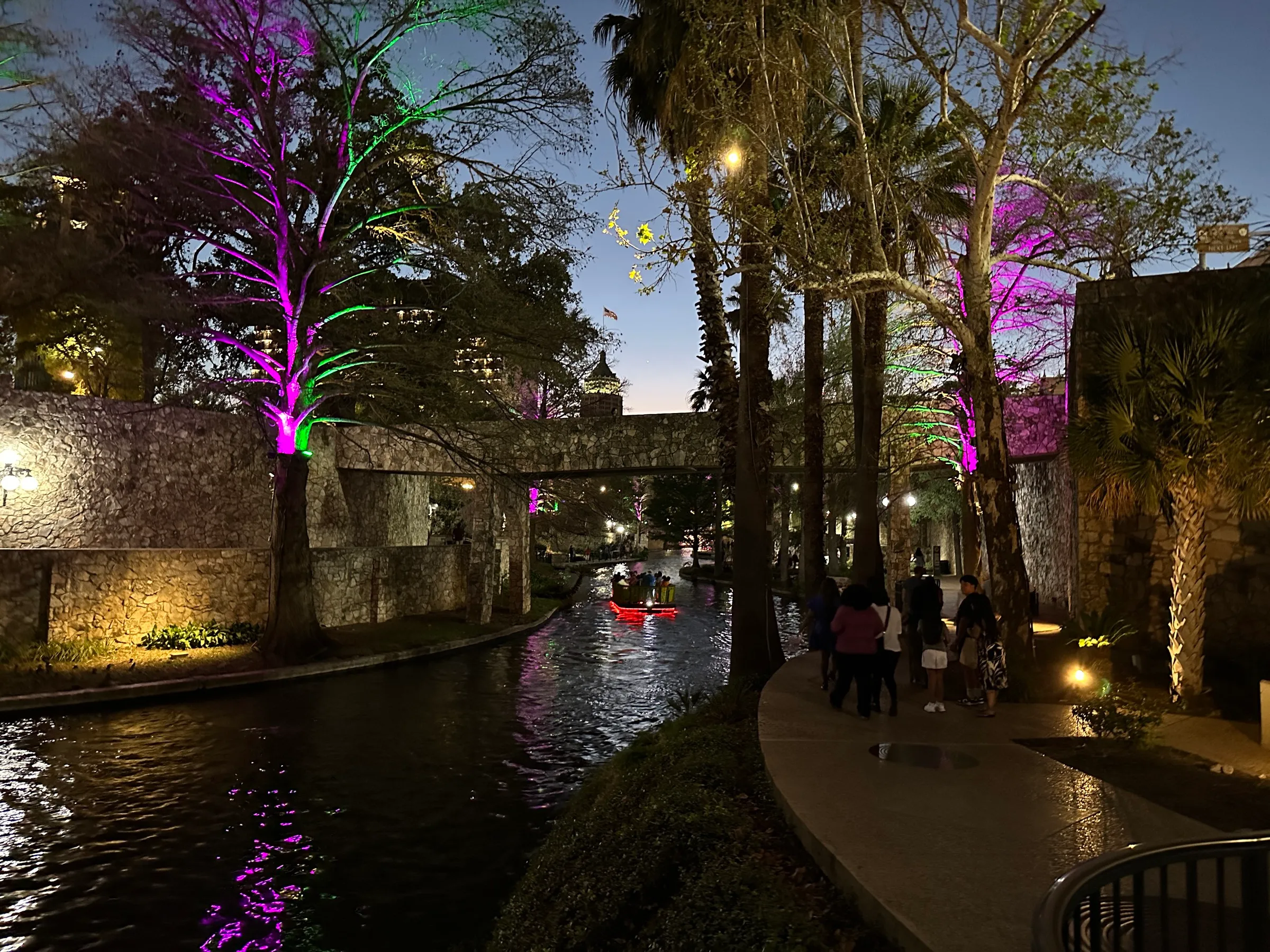Restaurant terraces, cypress trees and stone footbridges along the San Antonio River Walk at night