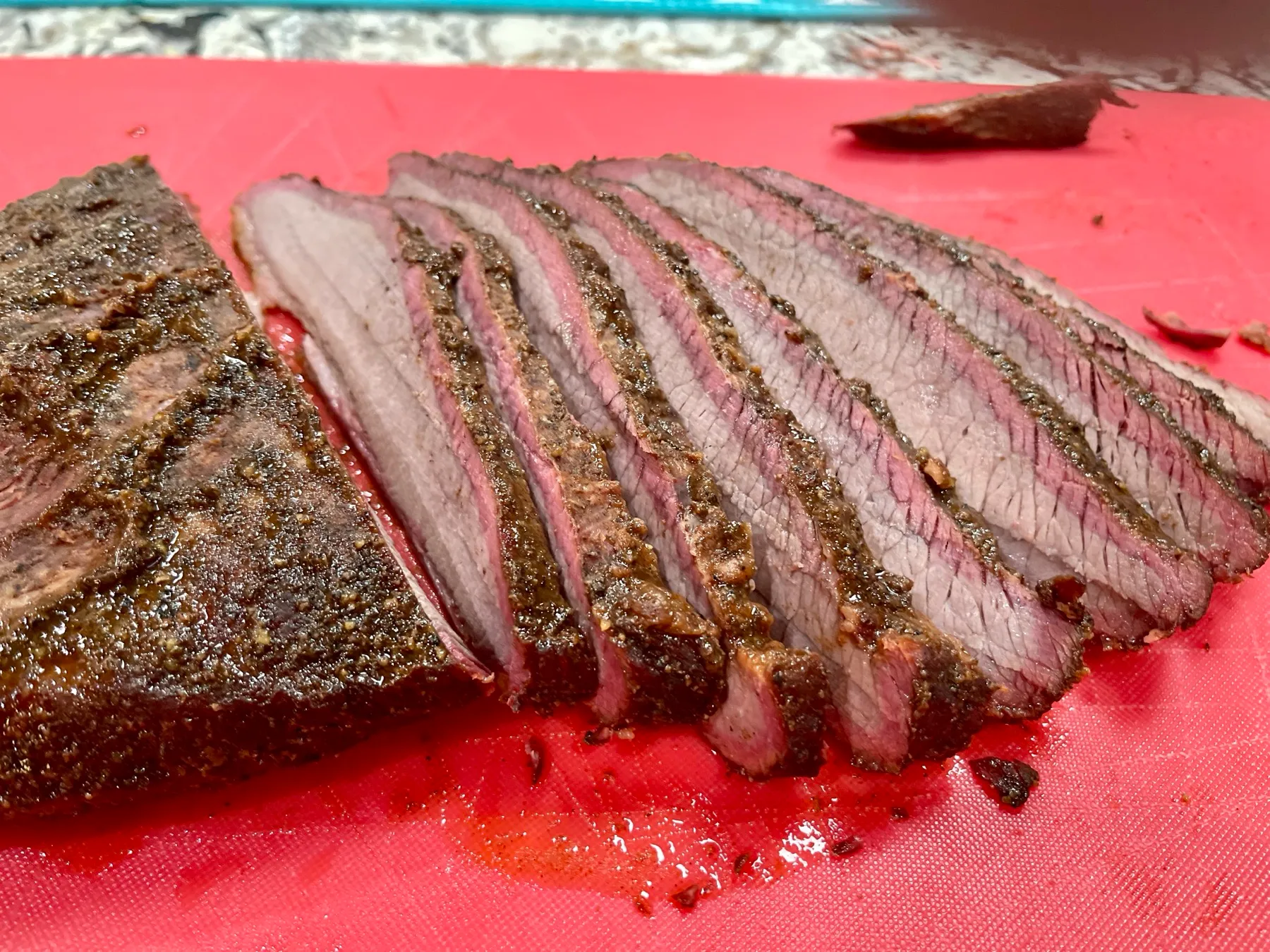 A sliced smoked beef brisket showing a pink smoke ring