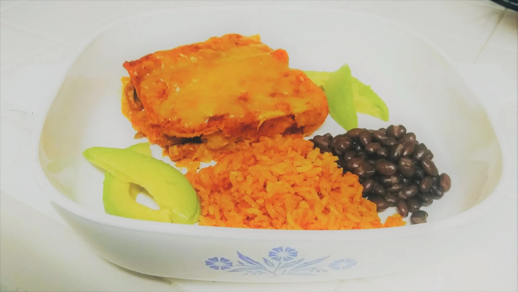 Chicken enchiladas under red sauce with melted cheddar