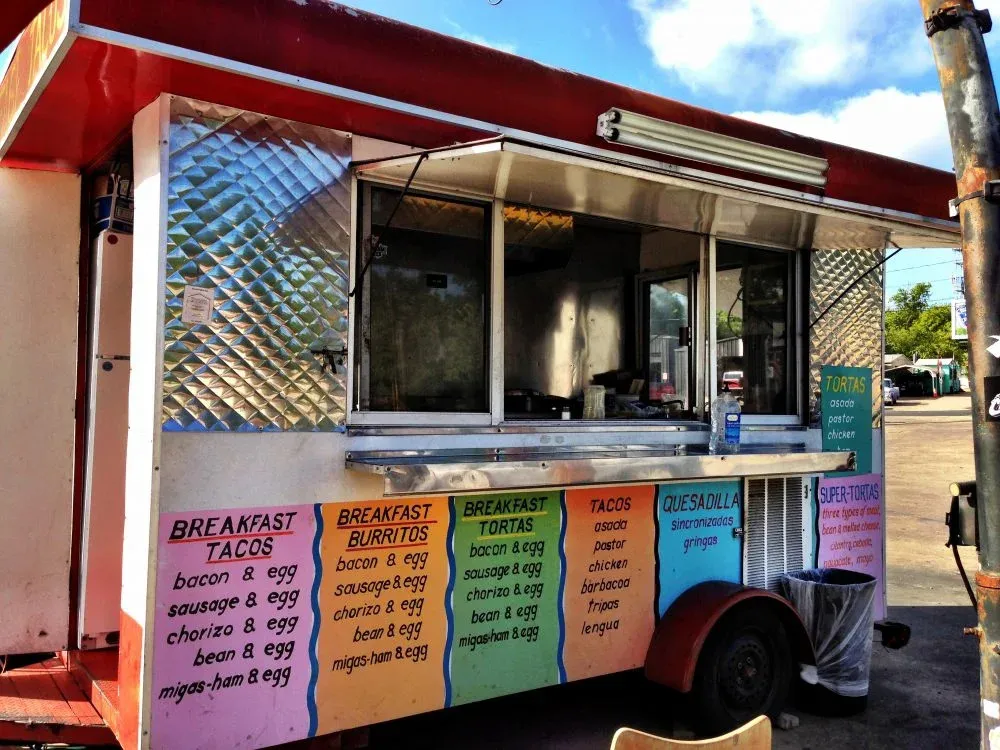 El Primo's red-and-silver South First Street taco trailer with its service window and painted menu open
