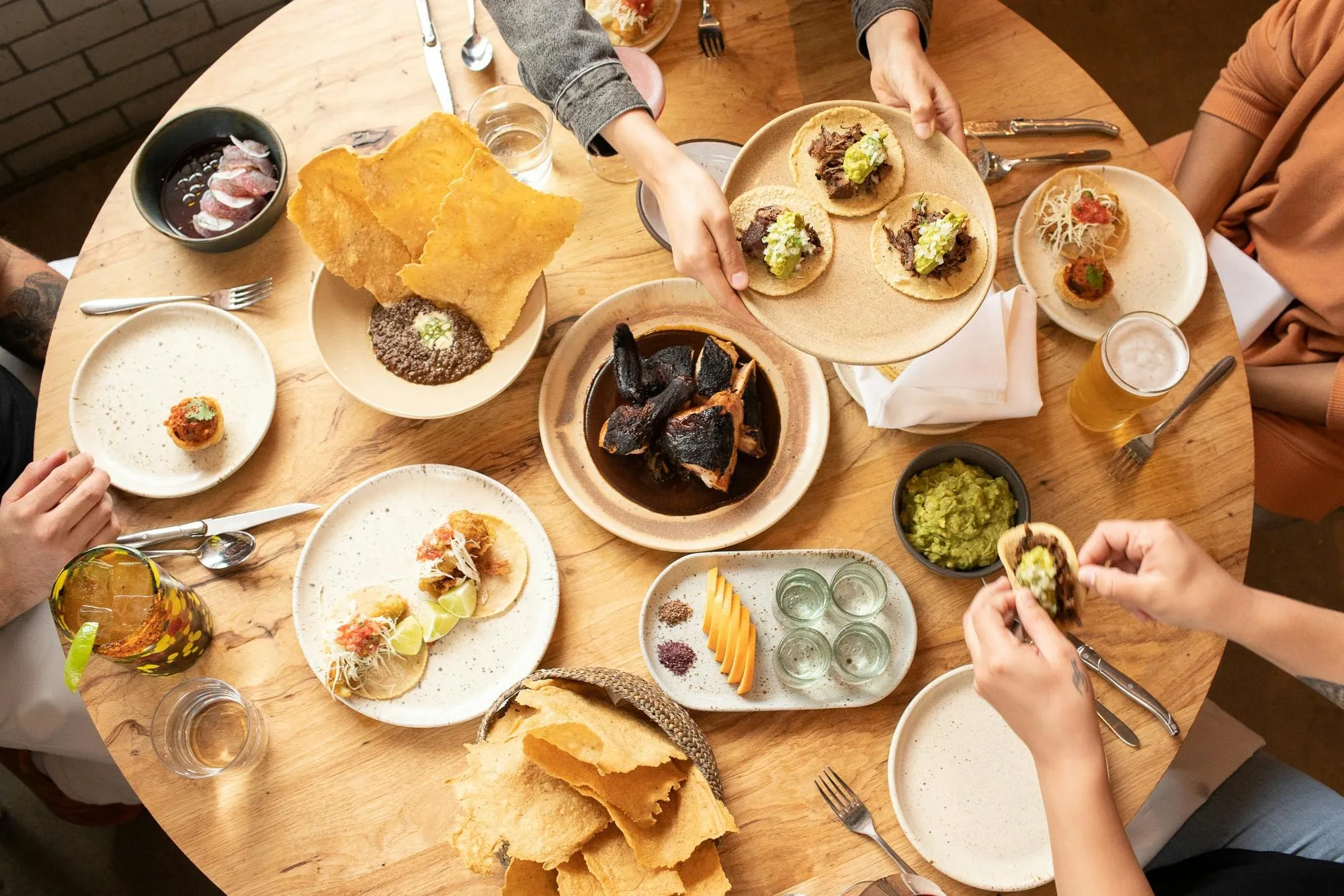 An overhead Suerte table set with tacos, tostadas, chips, small plates and drinks