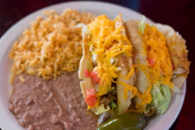 A beef puffy taco at Ray's Drive Inn with lettuce, tomato, and shredded cheese