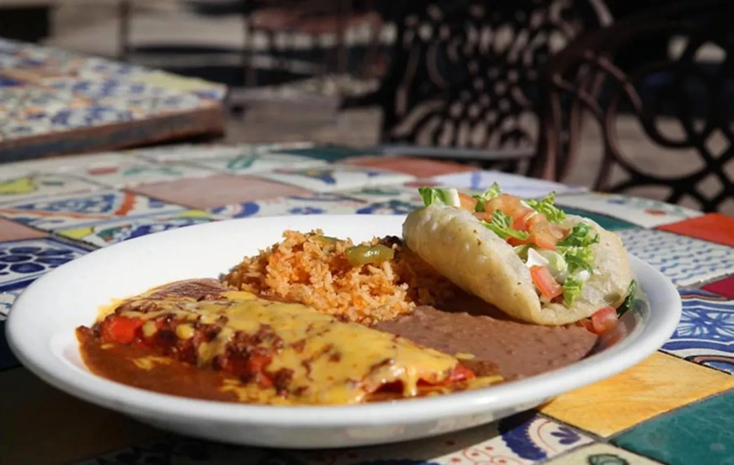 A Los Barrios plate with a puffy taco, cheese enchilada, rice, and refried beans