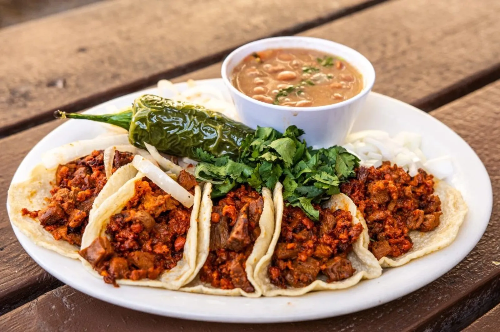 Four tacos on handmade tortillas at Pete's Tako House with a grilled jalapeño and beans