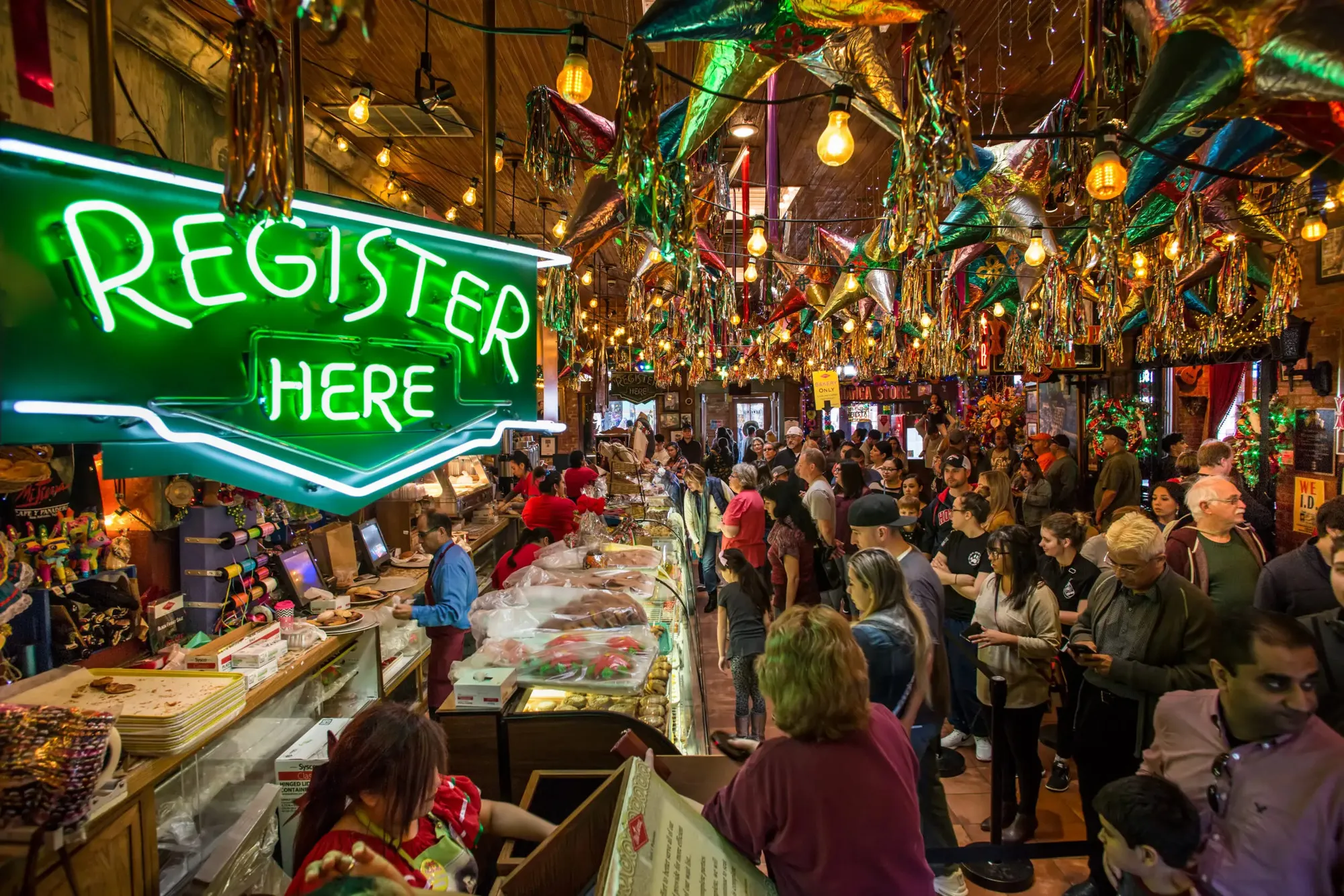 Mi Tierra's crowded bakery counter under neon, piñatas, and strings of lights