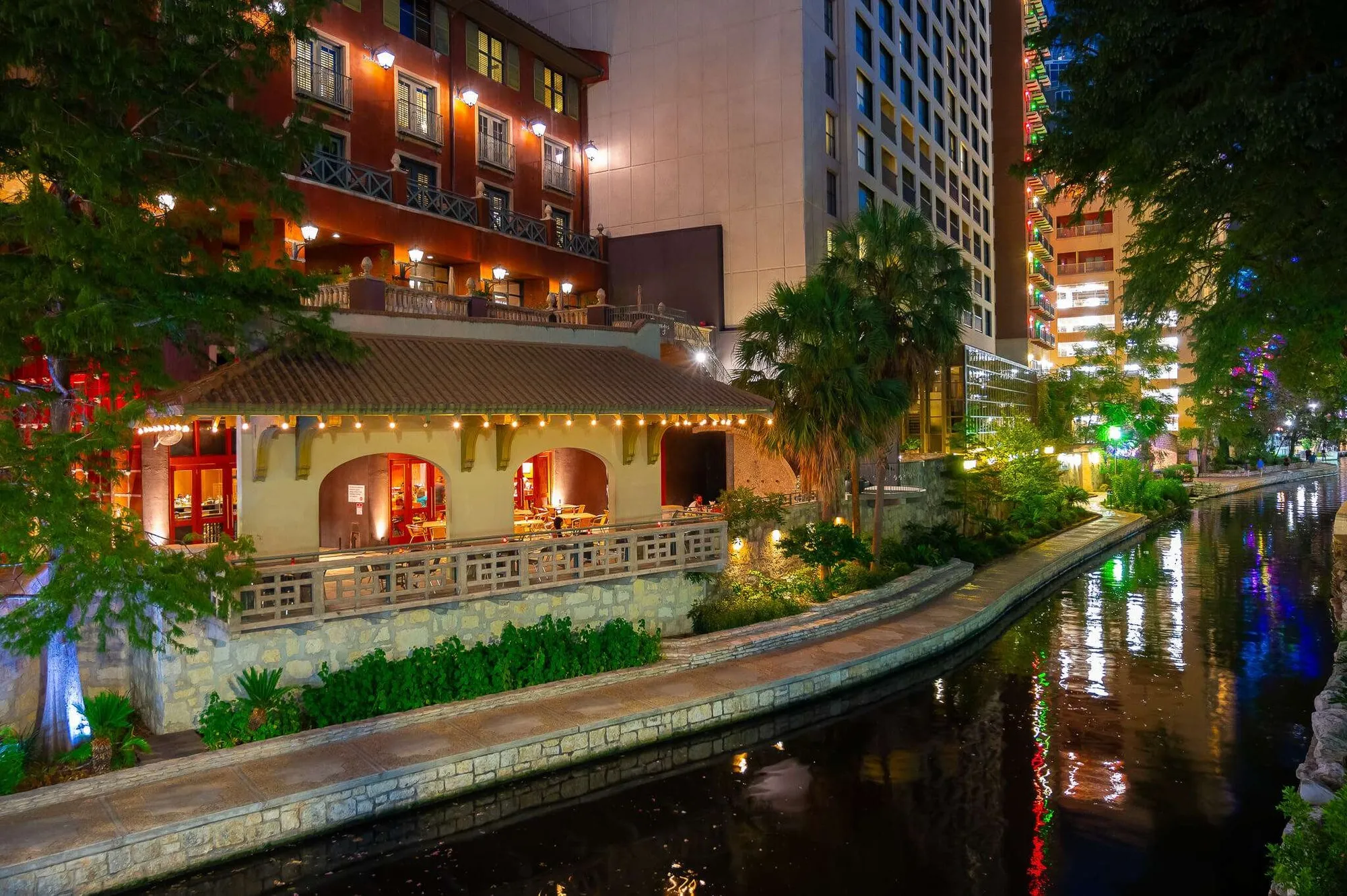 Acenar's illuminated patio and dining room beside the San Antonio River Walk at night