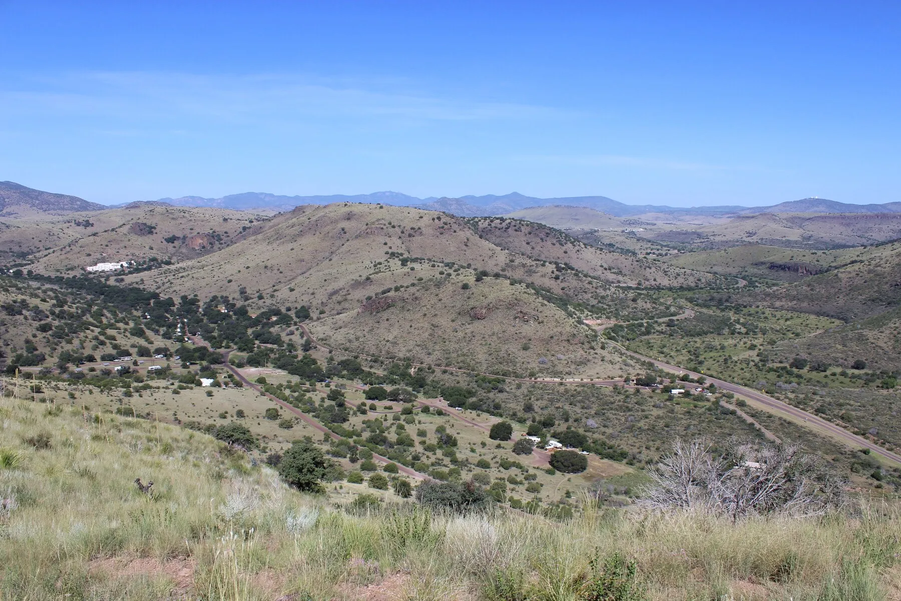 Wide view across Davis Mountains State Park with Indian Lodge at left and a road winding through the hills