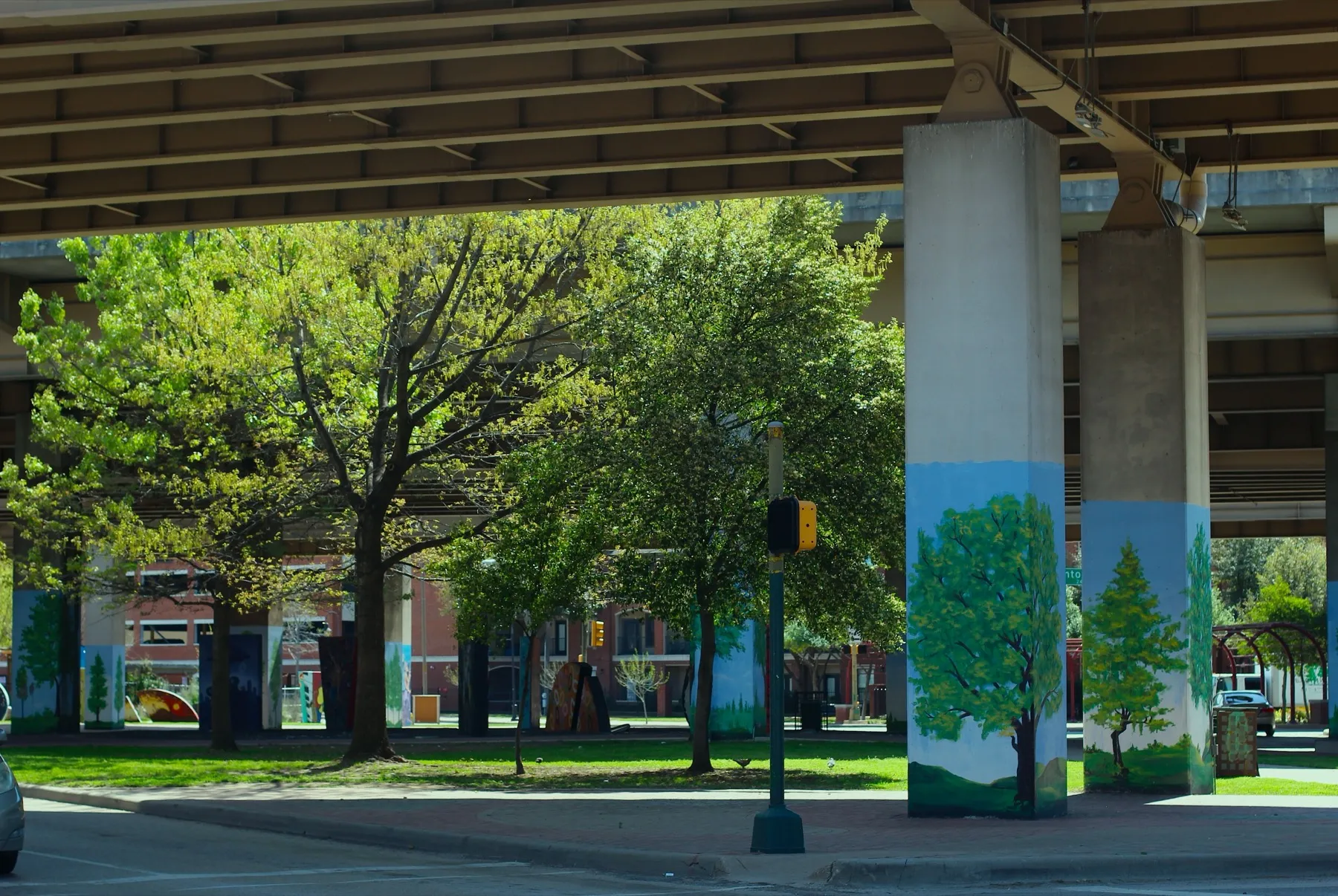 Painted tree murals wrapping freeway support columns in Deep Ellum
