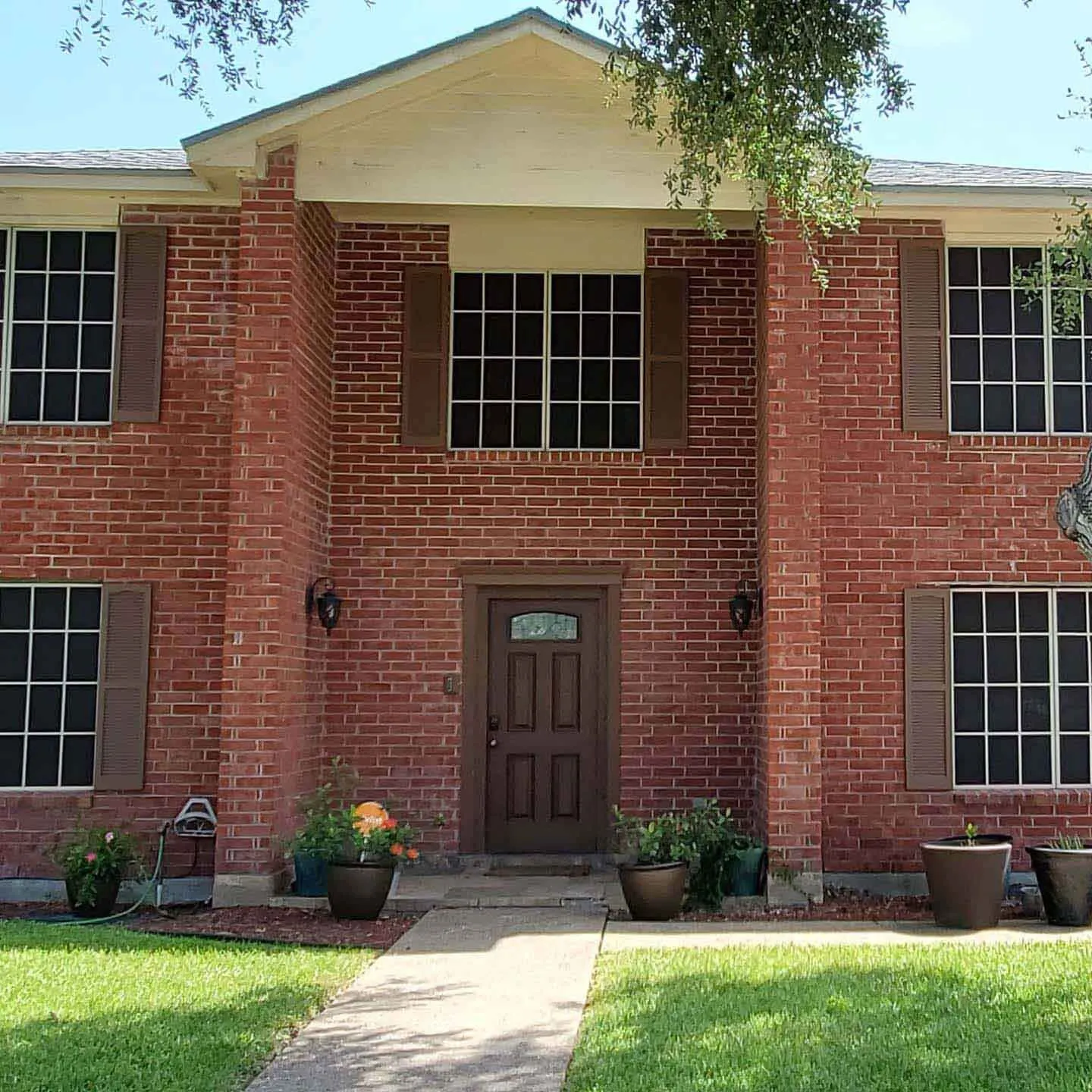 Dark solar screens installed across the windows of a two-story brick house