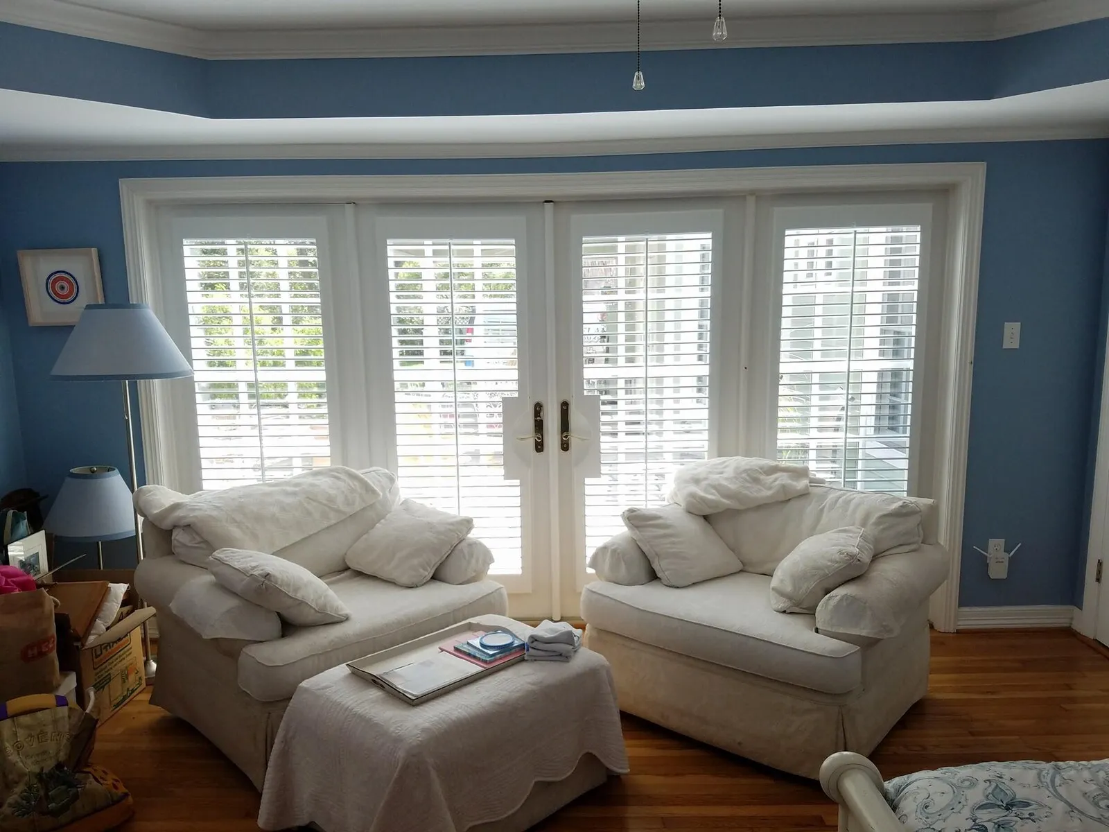 White plantation shutters fitted across French doors in a blue-walled living room