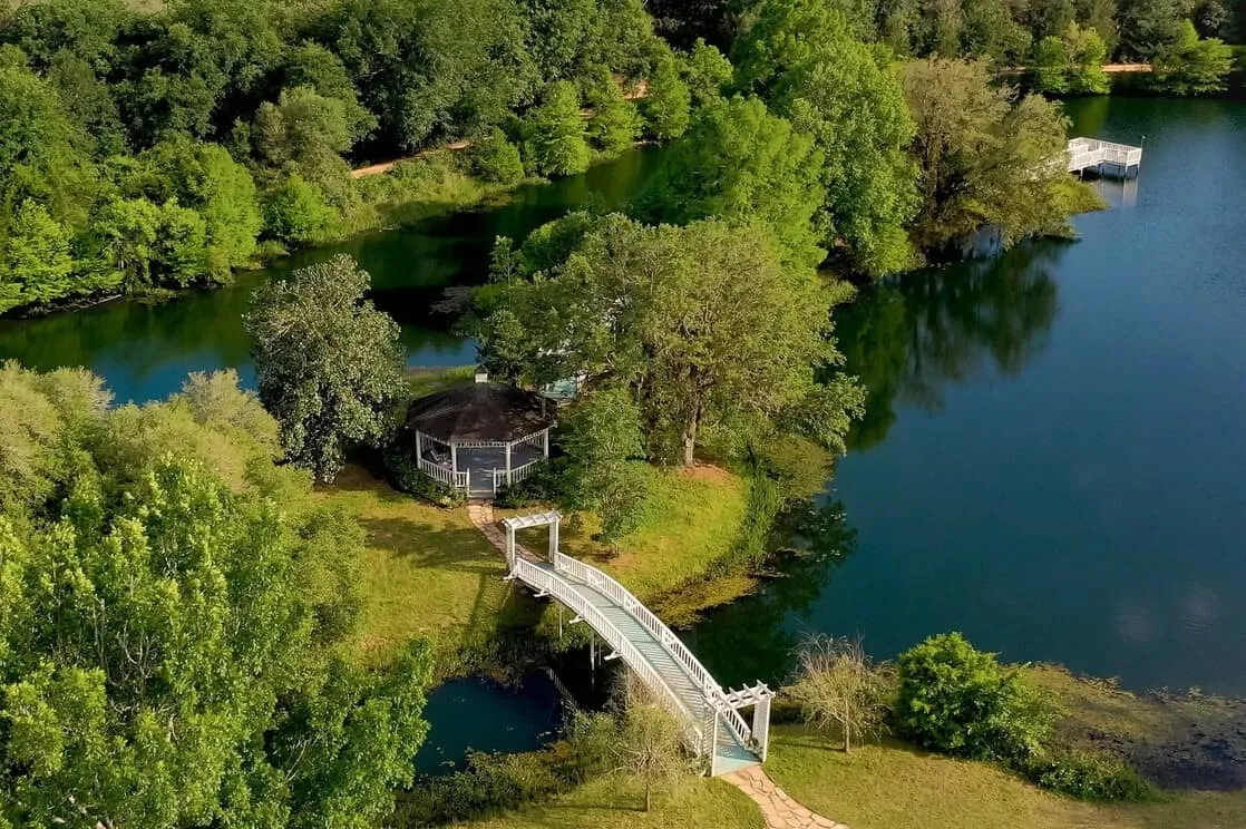 Aerial view of a lakeside gazebo and trees at BlissWood Bed and Breakfast Ranch