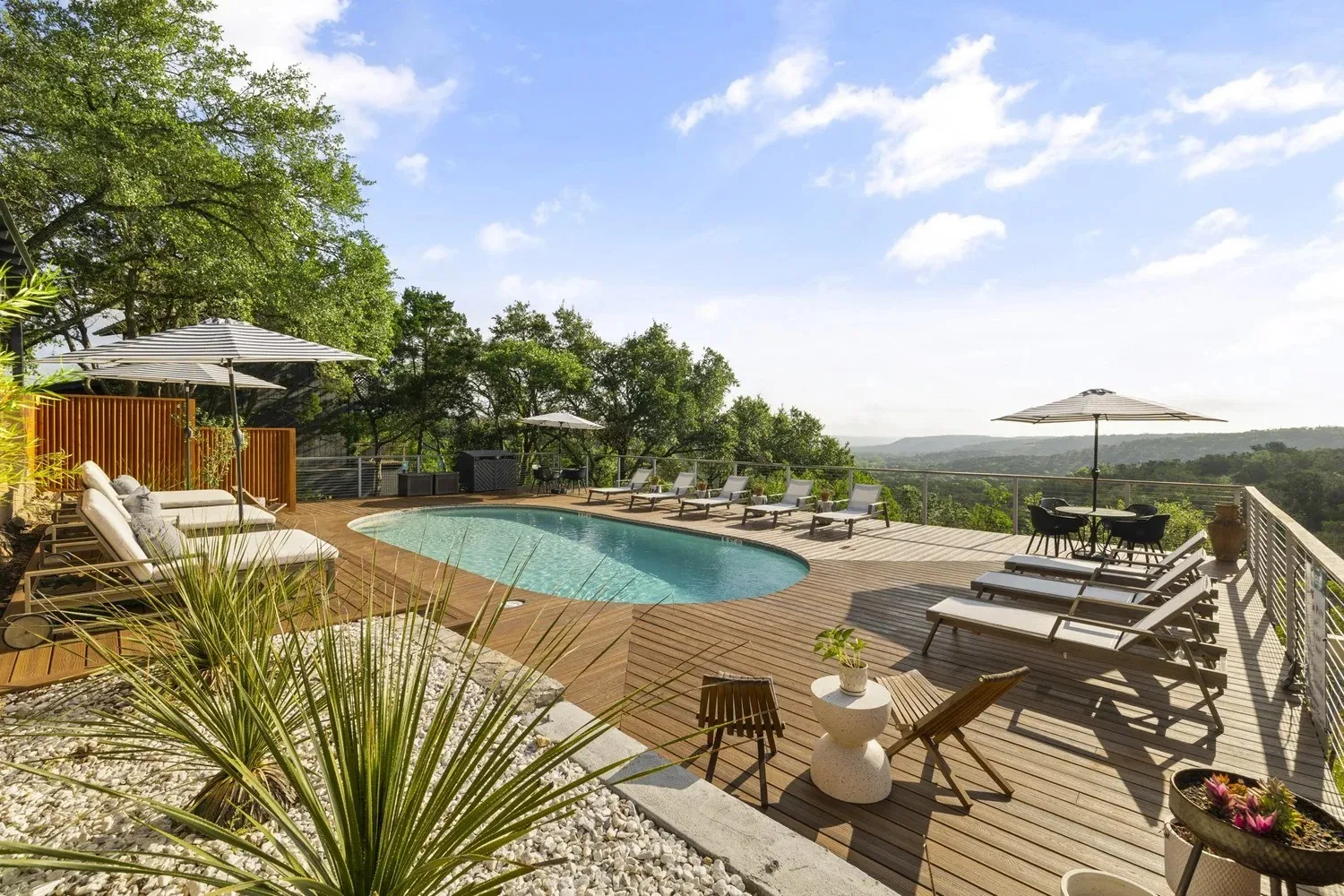 Pool and lounge chairs overlooking wooded hills at The Bygone in Wimberley
