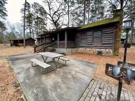 Log cabin with a covered porch and picnic table at Caddo Lake State Park