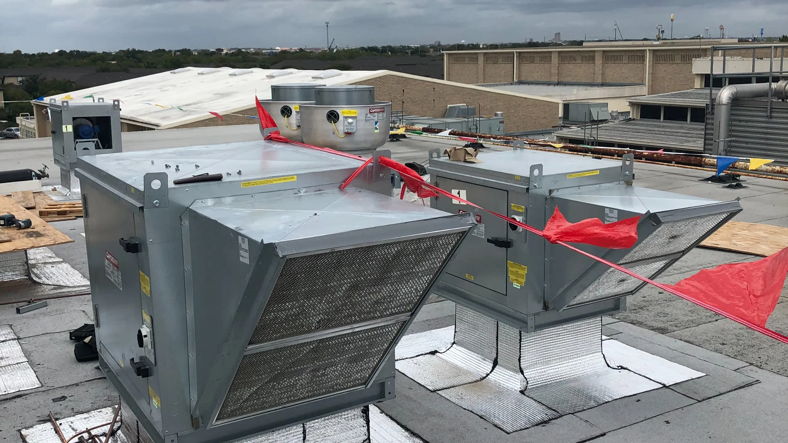 Commercial rooftop ventilation equipment during an installation, with red safety tape around the work area
